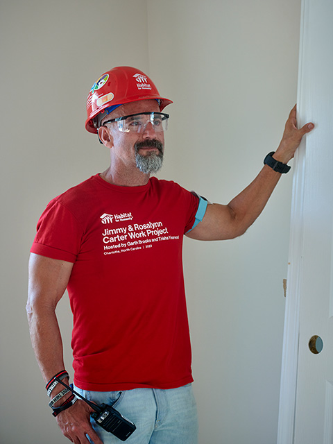Dr. Ernie wearing a red helmet and medical team shirt inside a white-painted room.