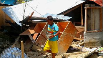 A young boy salvages belongings amid the rubble