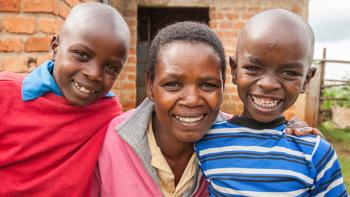 photo: a woman and two boys in front of a new house, Kenya