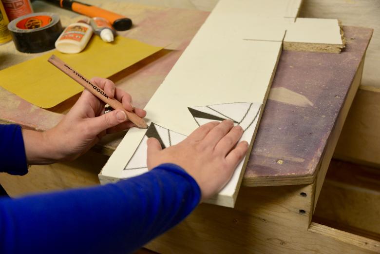 Theresa traces the paper template onto wood.