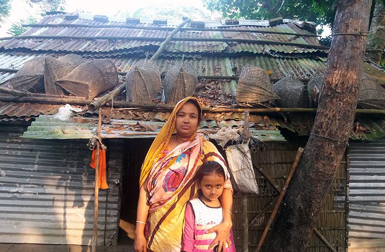 Sakina and her daughter Sadia in front of their old house in Bangladesh