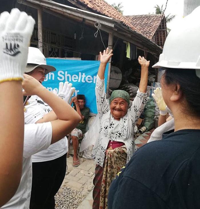 Atun, with raised hands, bonding with the volunteers working on her new home.