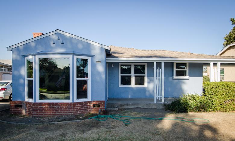 The same ranch home with new roof, new siding and fresh blue paint.