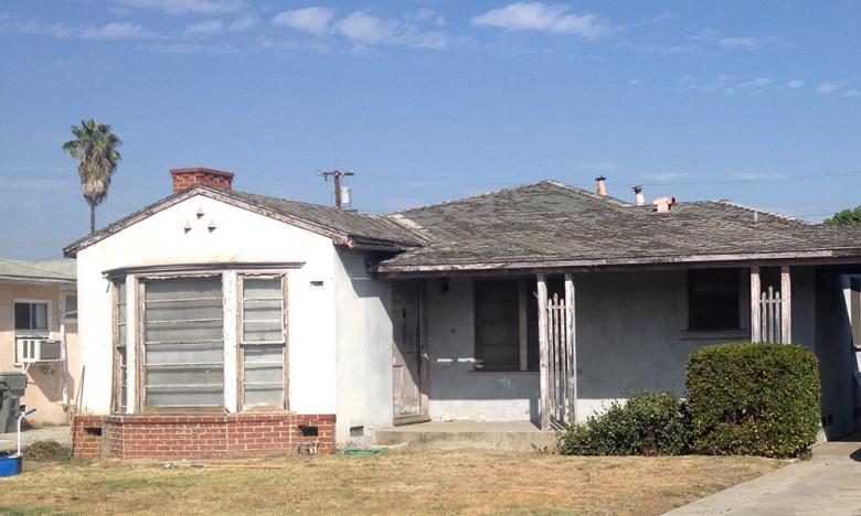 Ranch home with damaged roof, rotting siding and peeling paint.