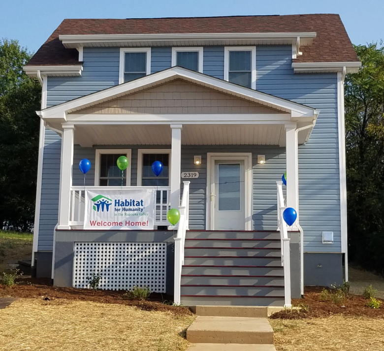 The same two-story house looking brand new with porch and welcome home banner.