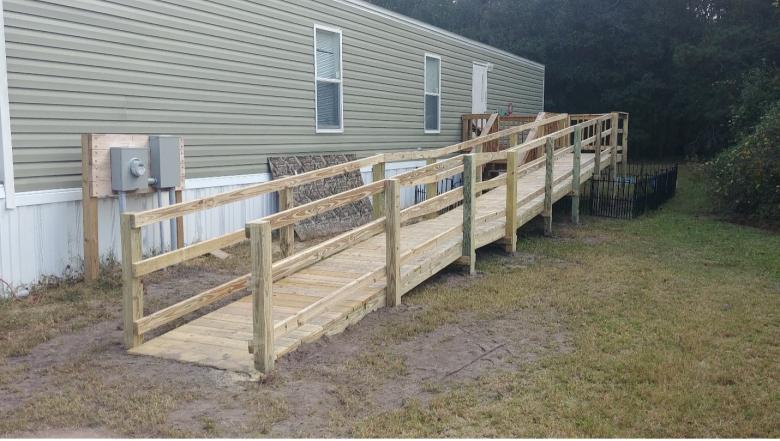A long wooden ramp leading up to a pale green house.