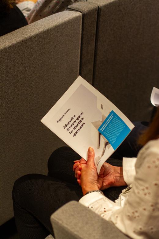 An event attendee holds an Empty Spaces to Homes toolkit developed by Habitat Great Britain.