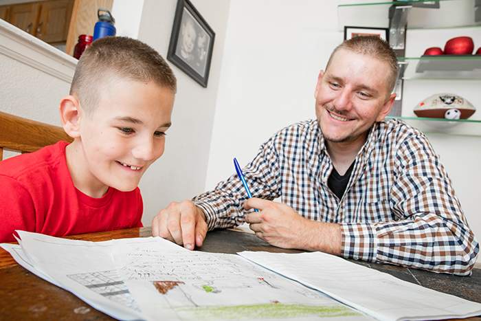 Justin helps his son Jordan with his homework in the dining room of their Habitat home in Colorado.