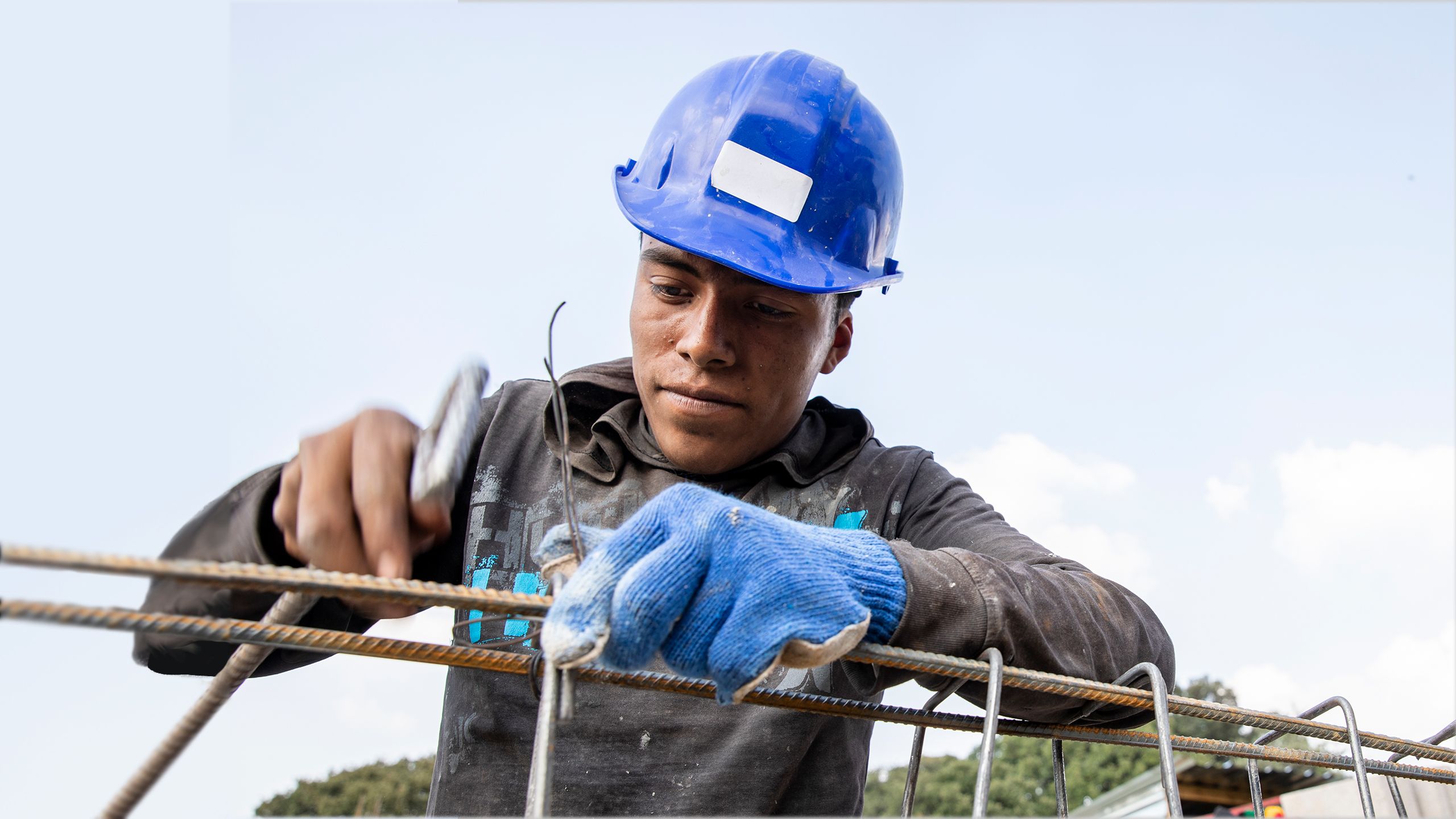 A volunteer adjusts wiring on a section of rebar.