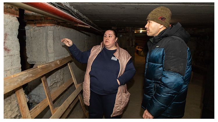 Ludmila and a staff member inspect the foundation of a building.