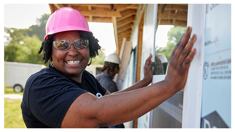 Marsha smiles as she holds a window in place for install.