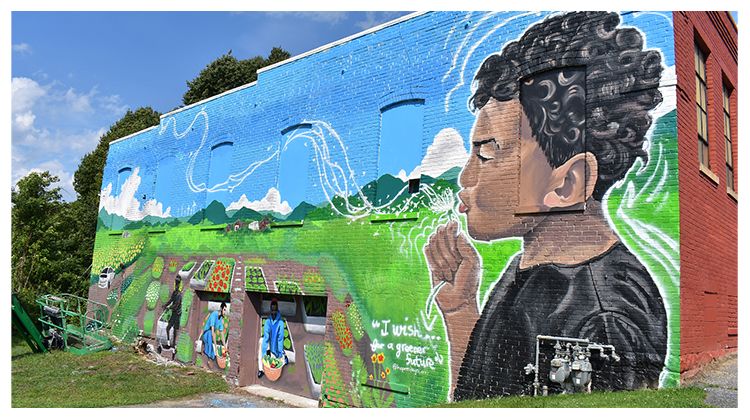 A large, colorful mural of a young Black boy blowing bubbles across an open landscape on the side of a building in Pittsfield.