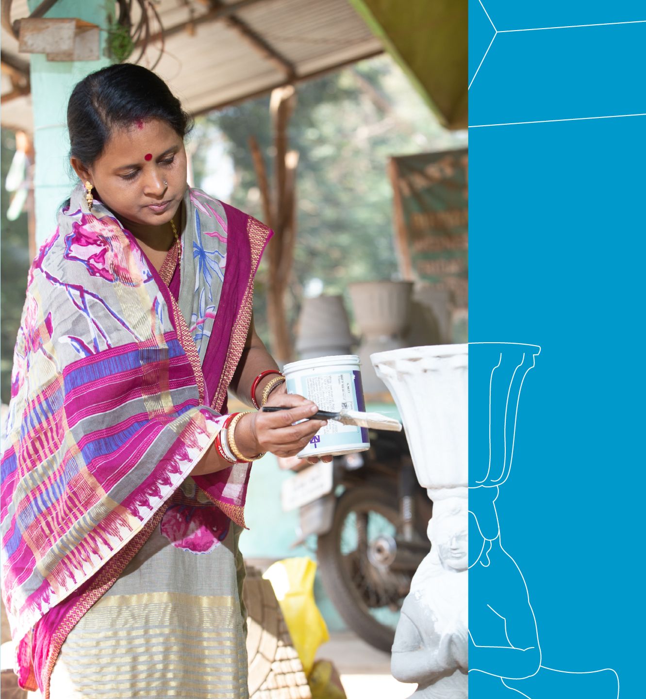 A woman with a pink and white sari applies white paint to a concrete statue.