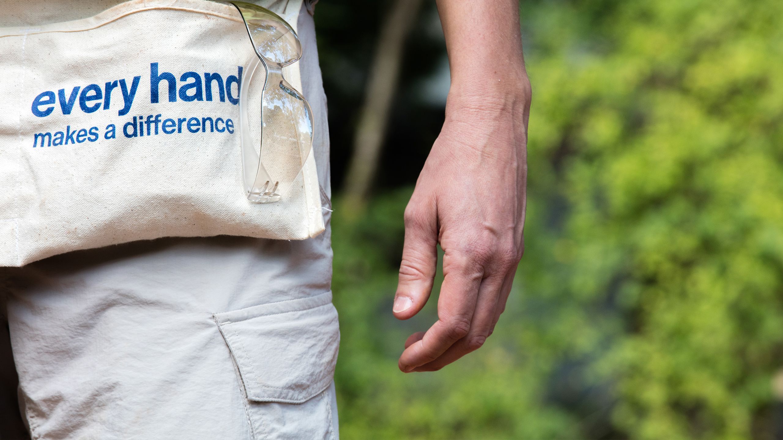 Closeup on hand of a Habitat volunteer wearing a nail apron reading "Every hand makes a difference."