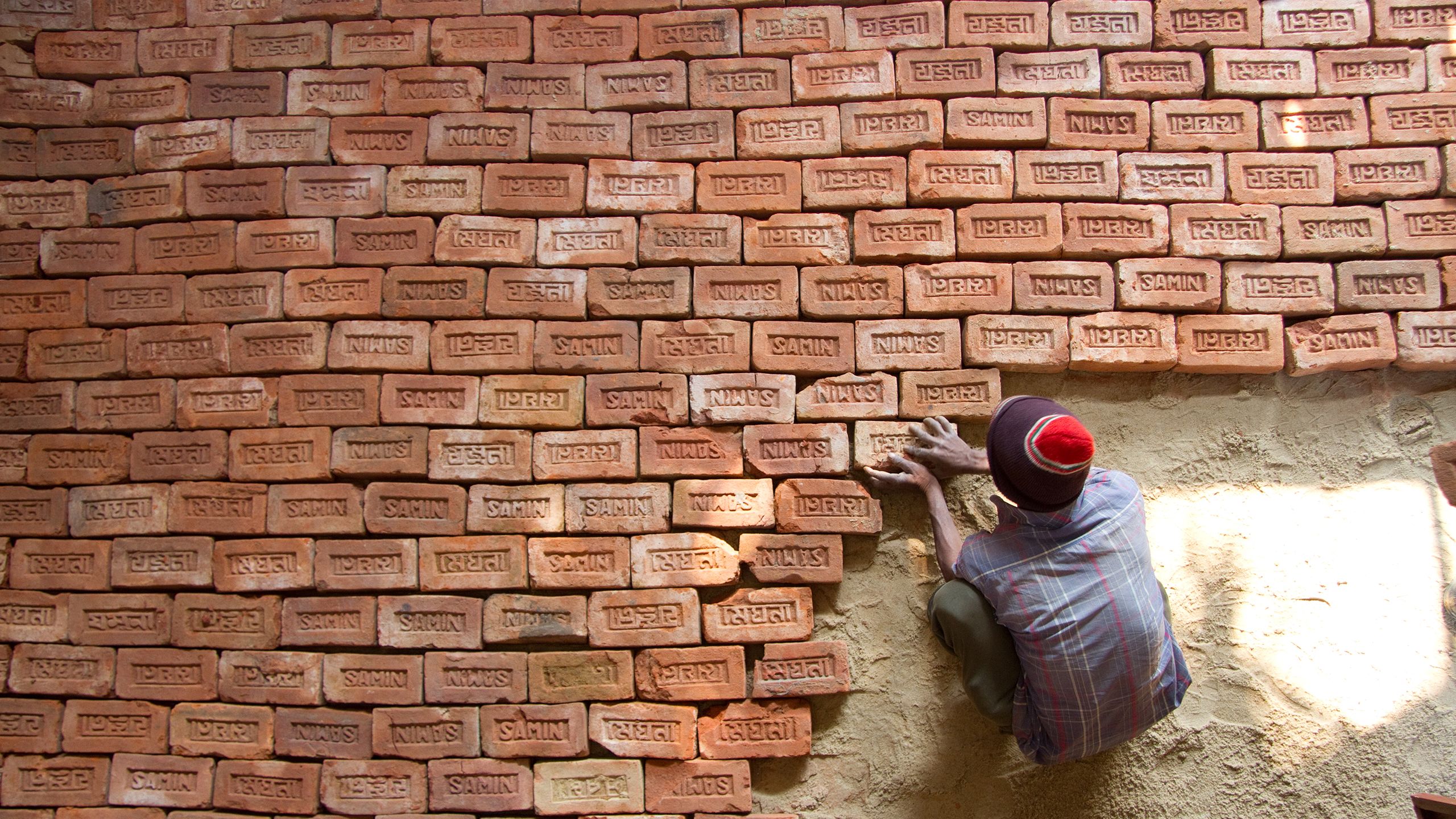 Volunteer lays a brick floor in a Habitat home in Bangladesh