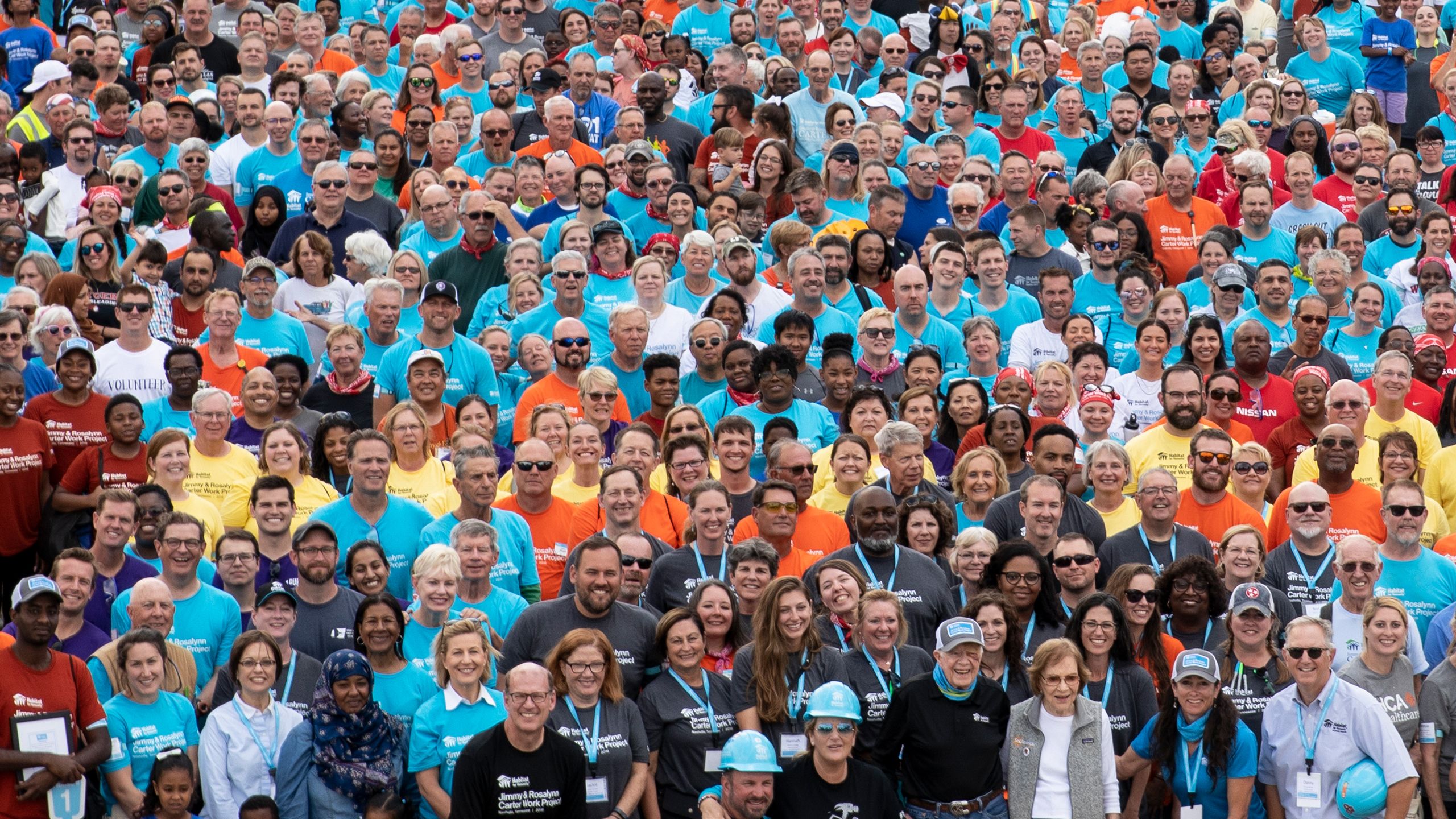 A large group of Habitat volunteers in colorful t-shirts at the 2019 Carter Work Project