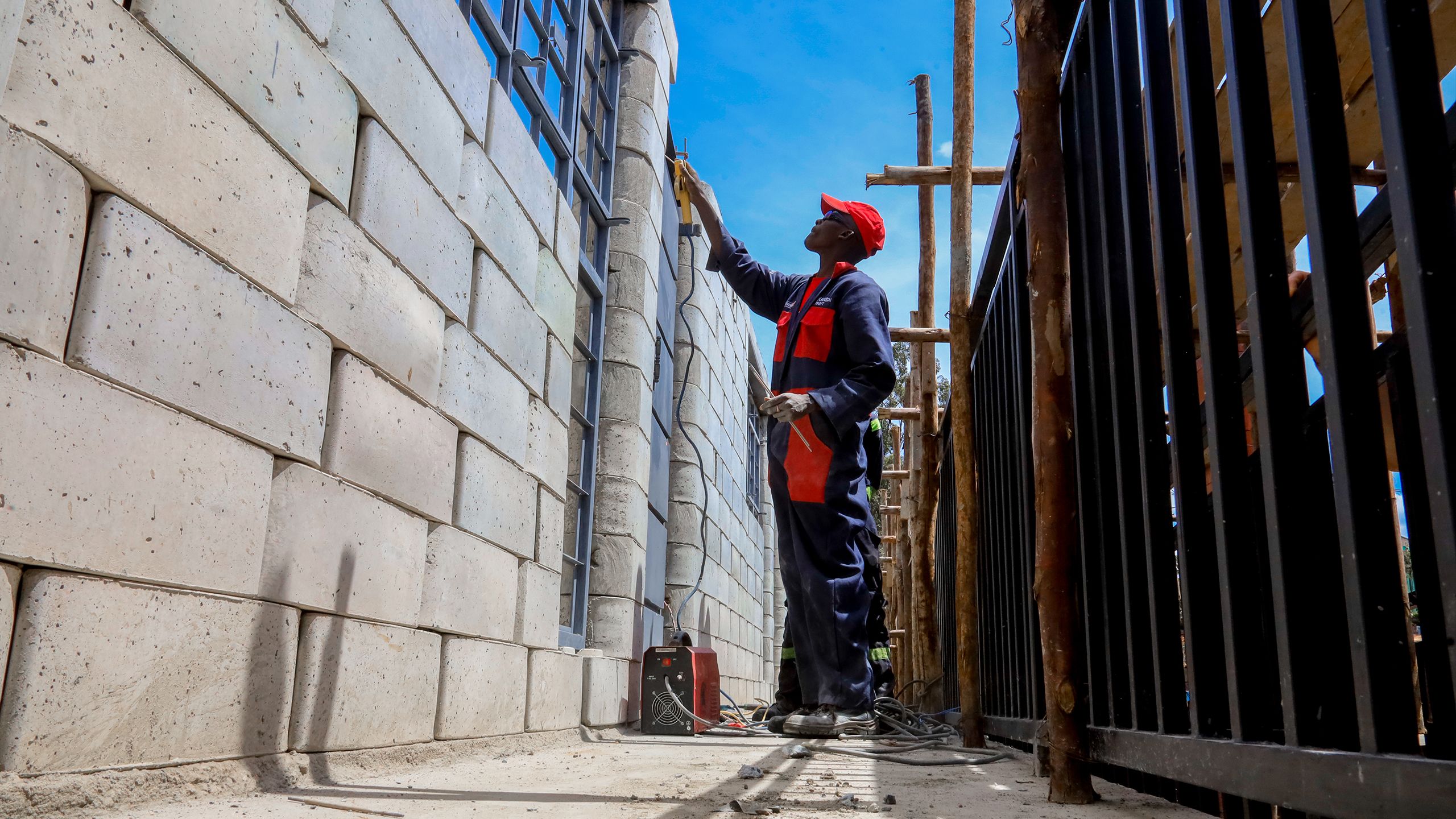 A builder puts the finishing touches on the wall of a library built with TwistBlocks.