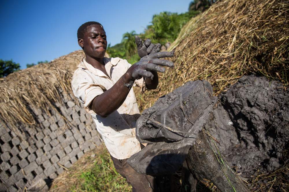 An assistant prepares the clay soil at David’s brickmaking site