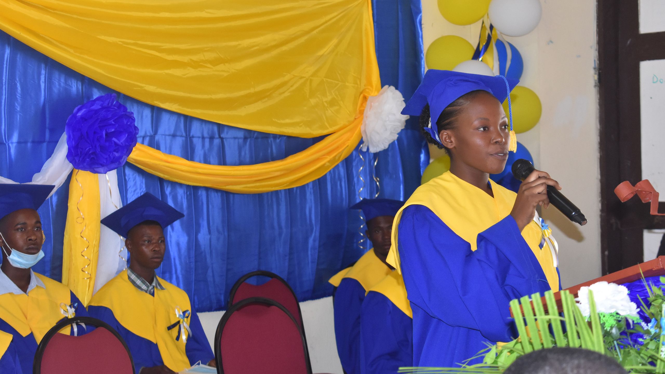 Young student in blue robe giving a graduation speech.