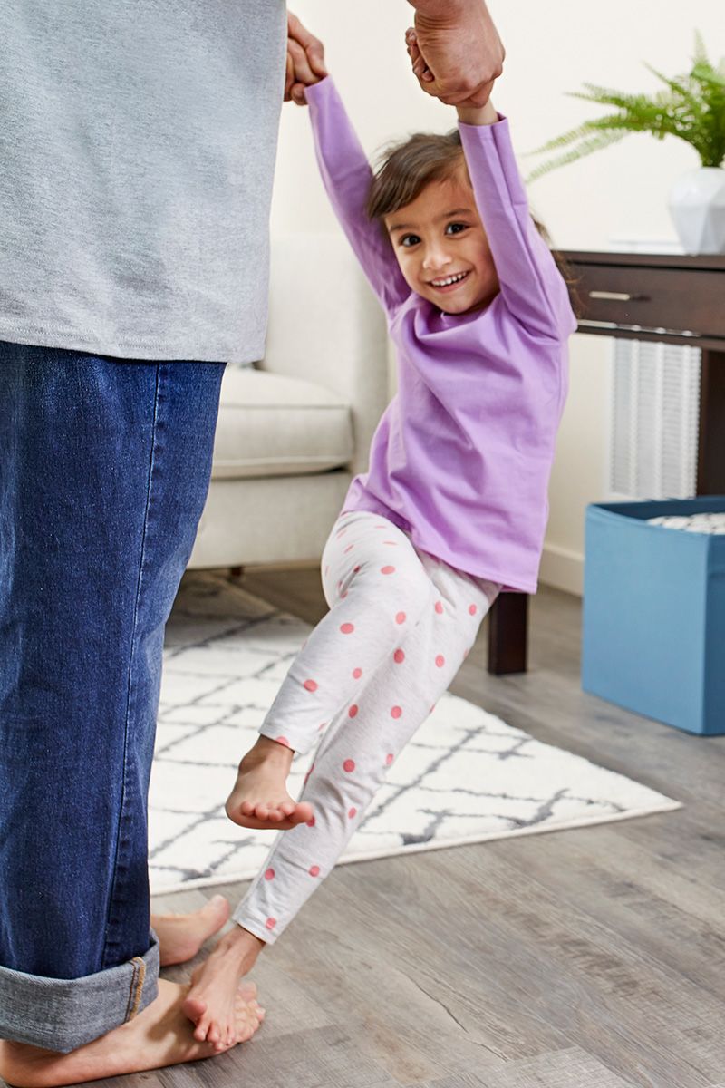 Emal dances playfully with his young daughter in the living room of their home, built during Home is the Key.