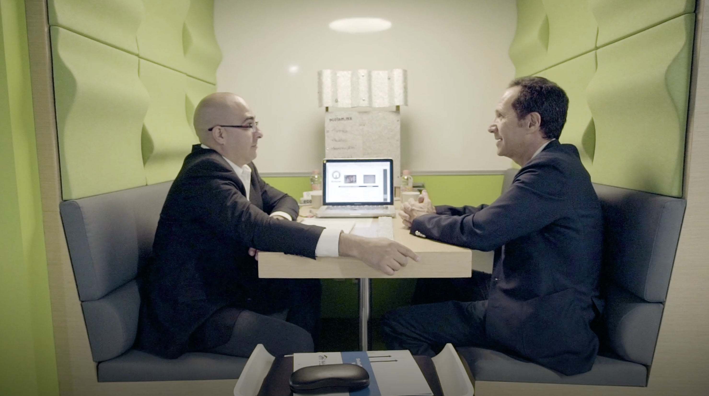 Two participants sit at a booth together and talk.