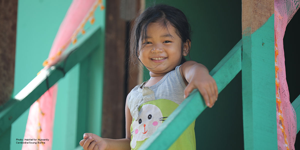 Young Cambodian girl smiling on her brightly colored stairs.