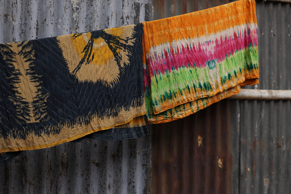 Colorful laundry hangs on a line in front of a wall made from corrugated metal.