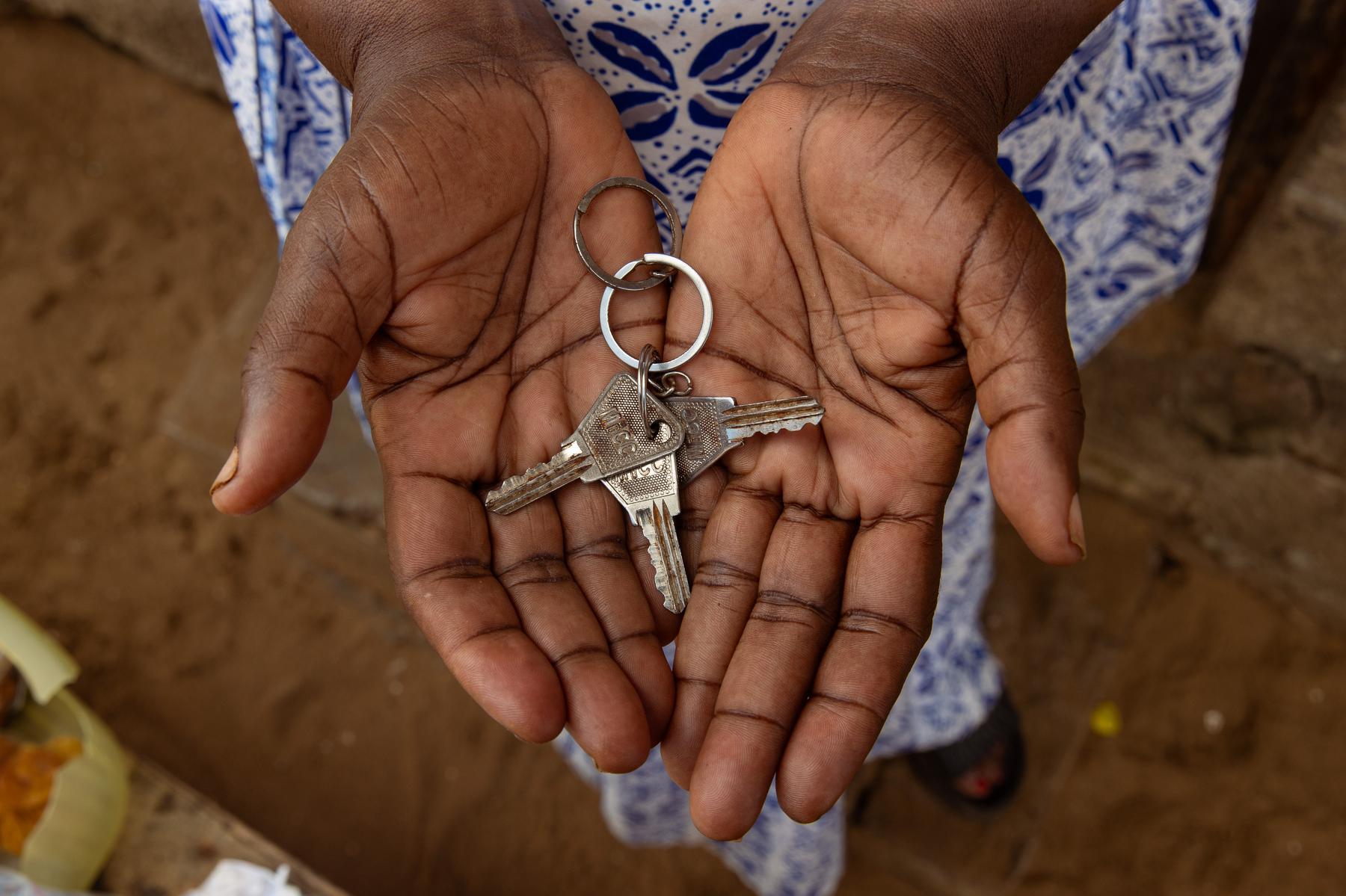 Two palms are open and holding a key chain with multiple keys.