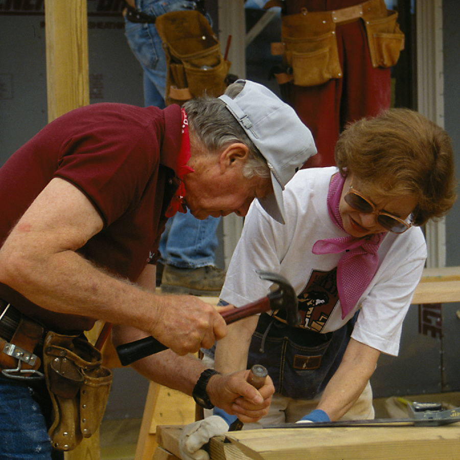 President and Mrs. Carter working together on hammering a piece of lumber.