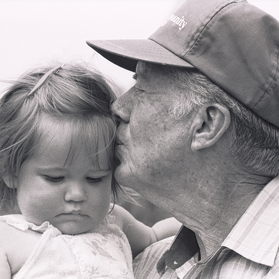Black and white photo close-up of President Carter kissing a baby on her cheek.