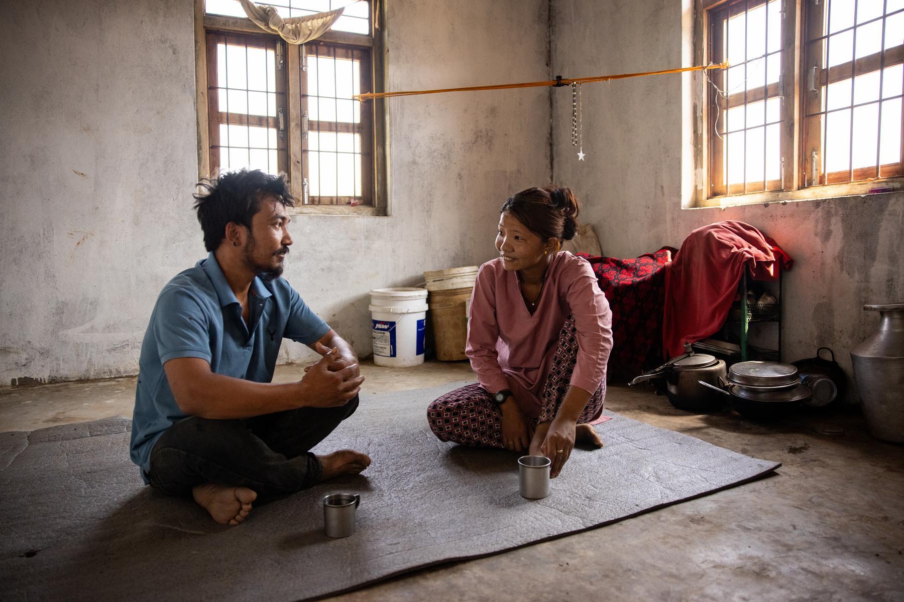 A man and a woman sit on a mat and look at each other while they are in deep conversation.