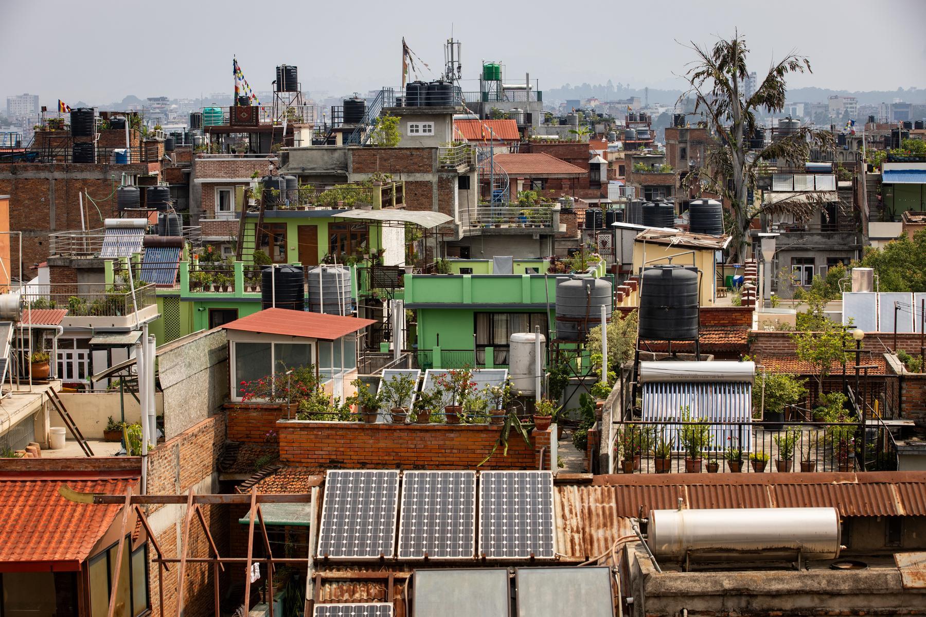 A landscape view of a city in Nepal featuring various types of buildings. There is a mountain in the distance.