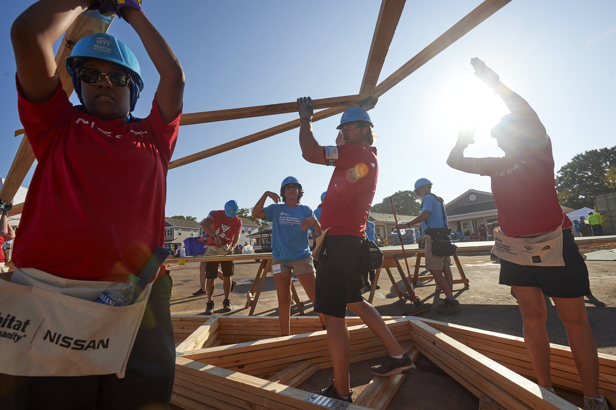 Volunteers lifting wooden framing on build site