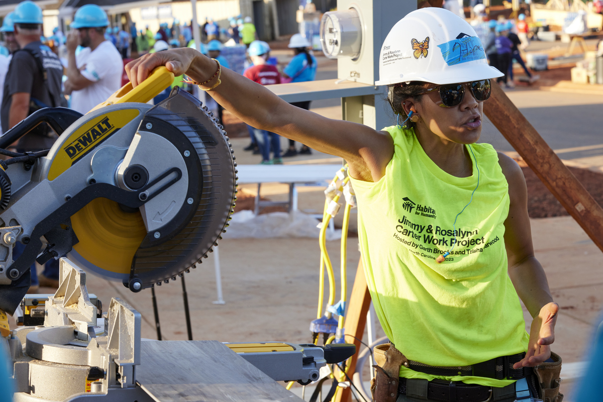 Construction volunteer giving safety instructions next to a saw