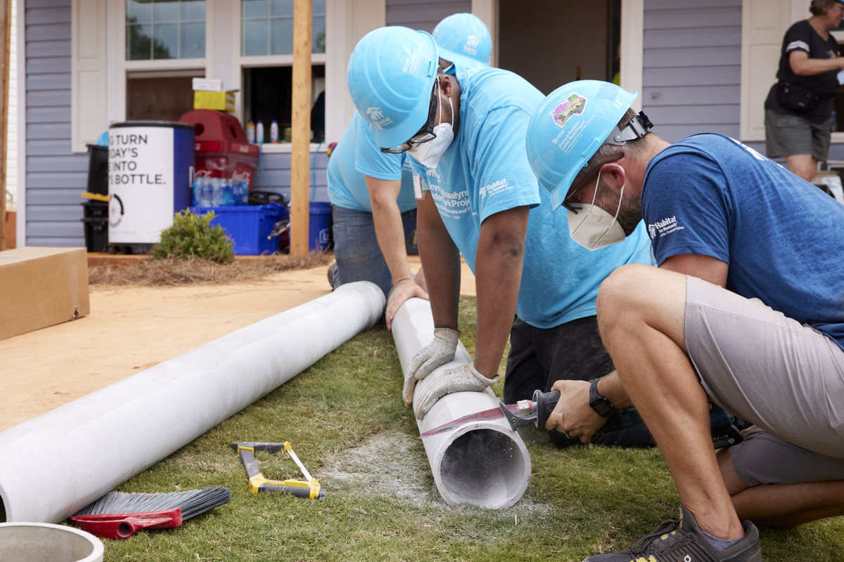 Habitat volunteers cutting a pipe