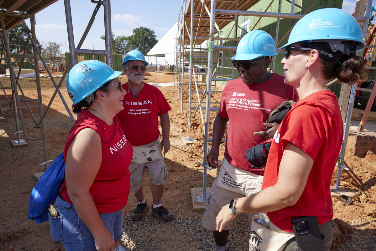 Several volunteers talking on a construction site, surrounded by scaffolding.