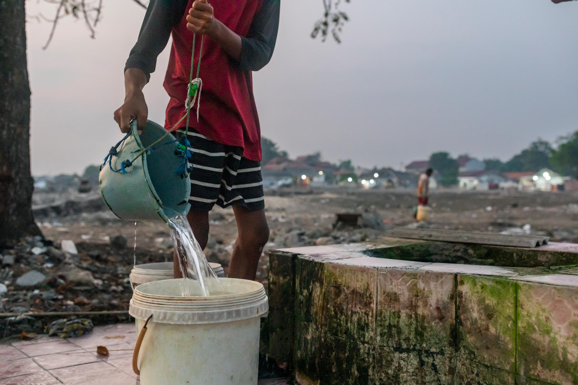 A person pours well water into a bucket.