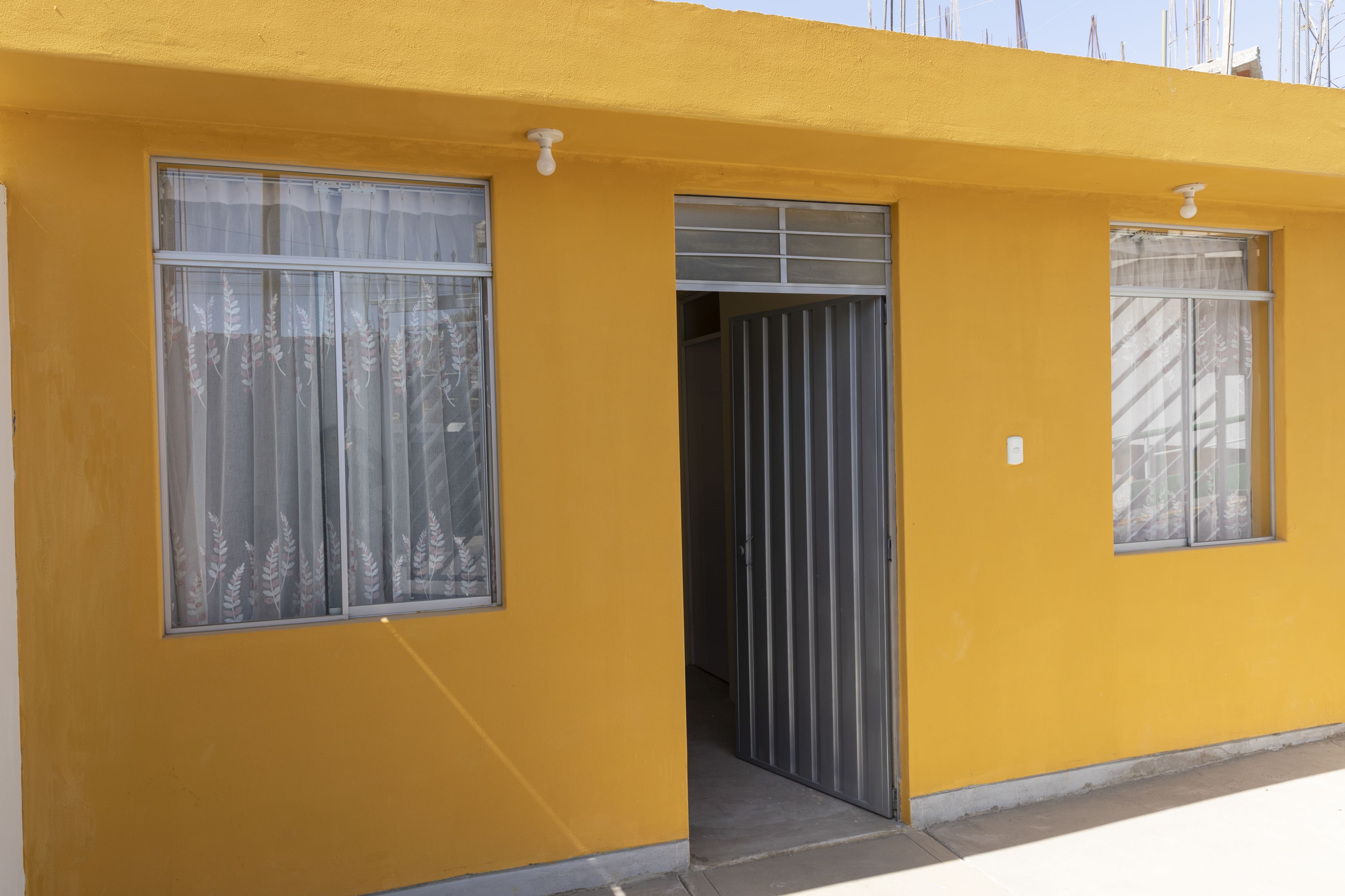 Exterior of a cement brick home in Peru, painted a bright golden yellow.