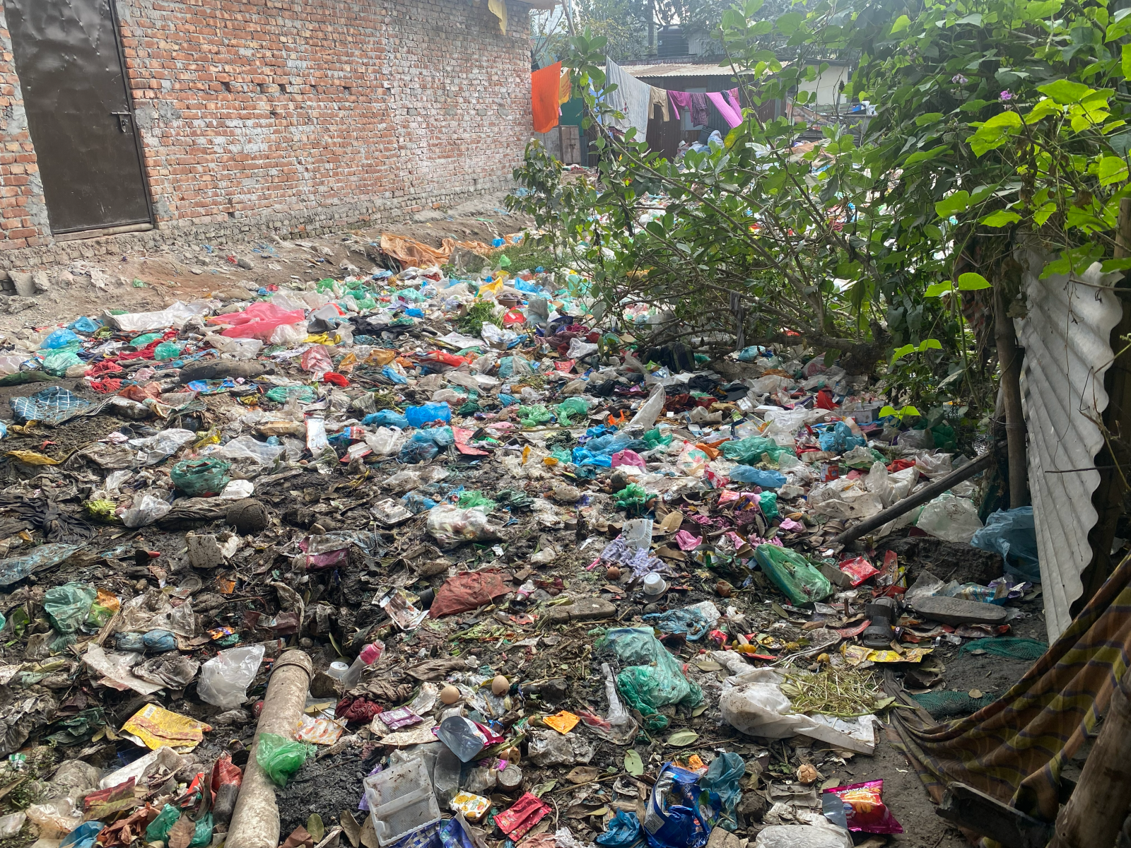 Outdoor area covered in garbage outside homes in the Bhashantek informal settlement. 