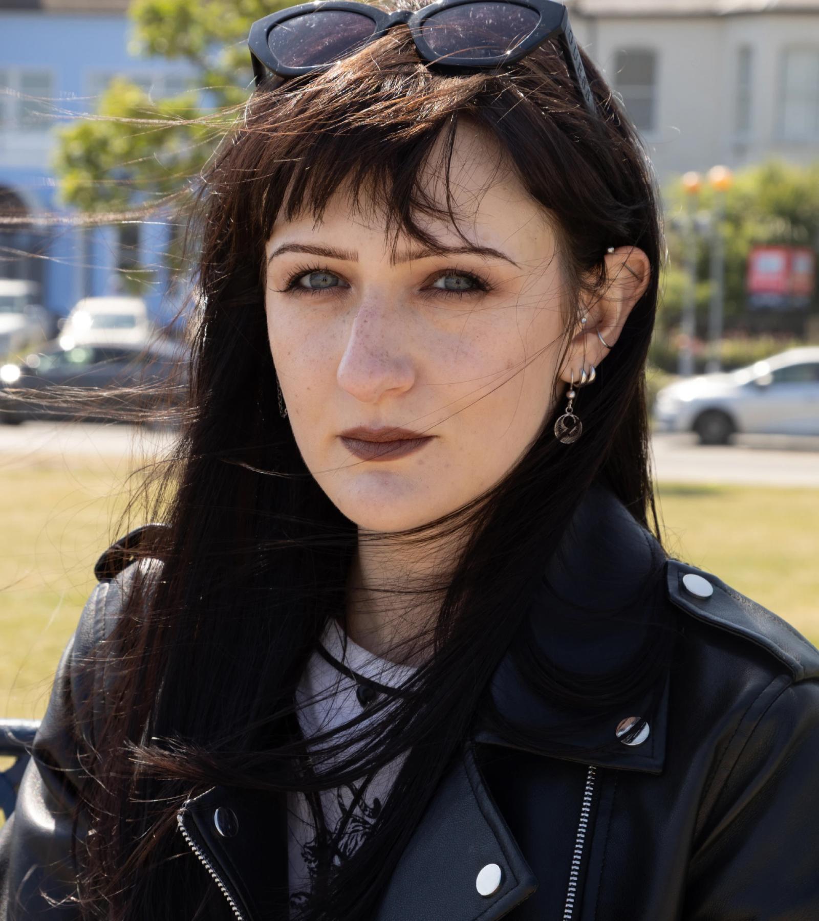 Ksenia looks at the camera with a serious expression on her face. She is wearing a leather jacket. She also has sunglasses on top of her head.