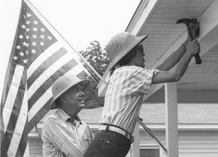 President Carter and Former First lady Rosalyn Carter working on a home build next to an American flag. 