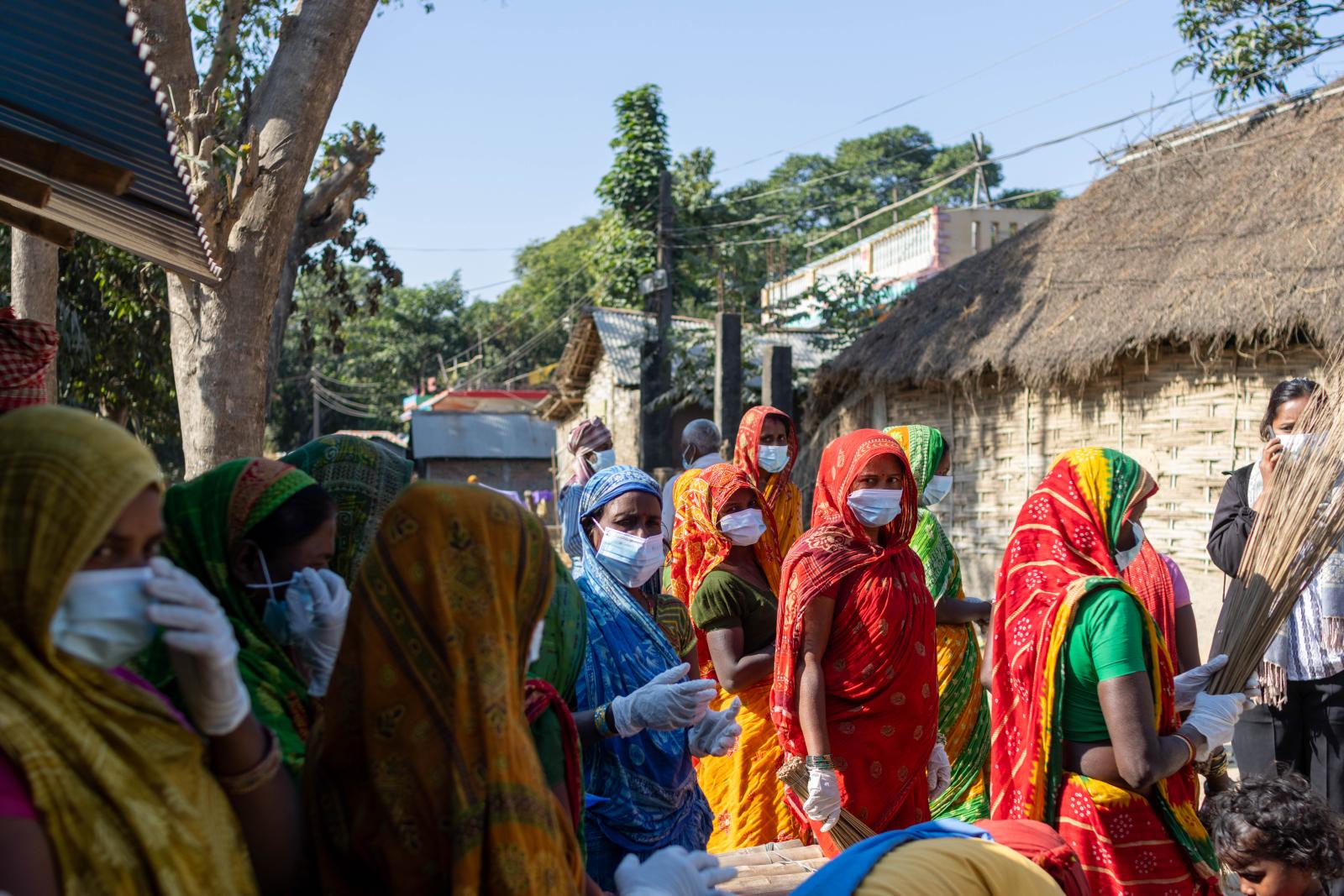 Crowd of women in colorful clothing wearing medical masks and gloves.