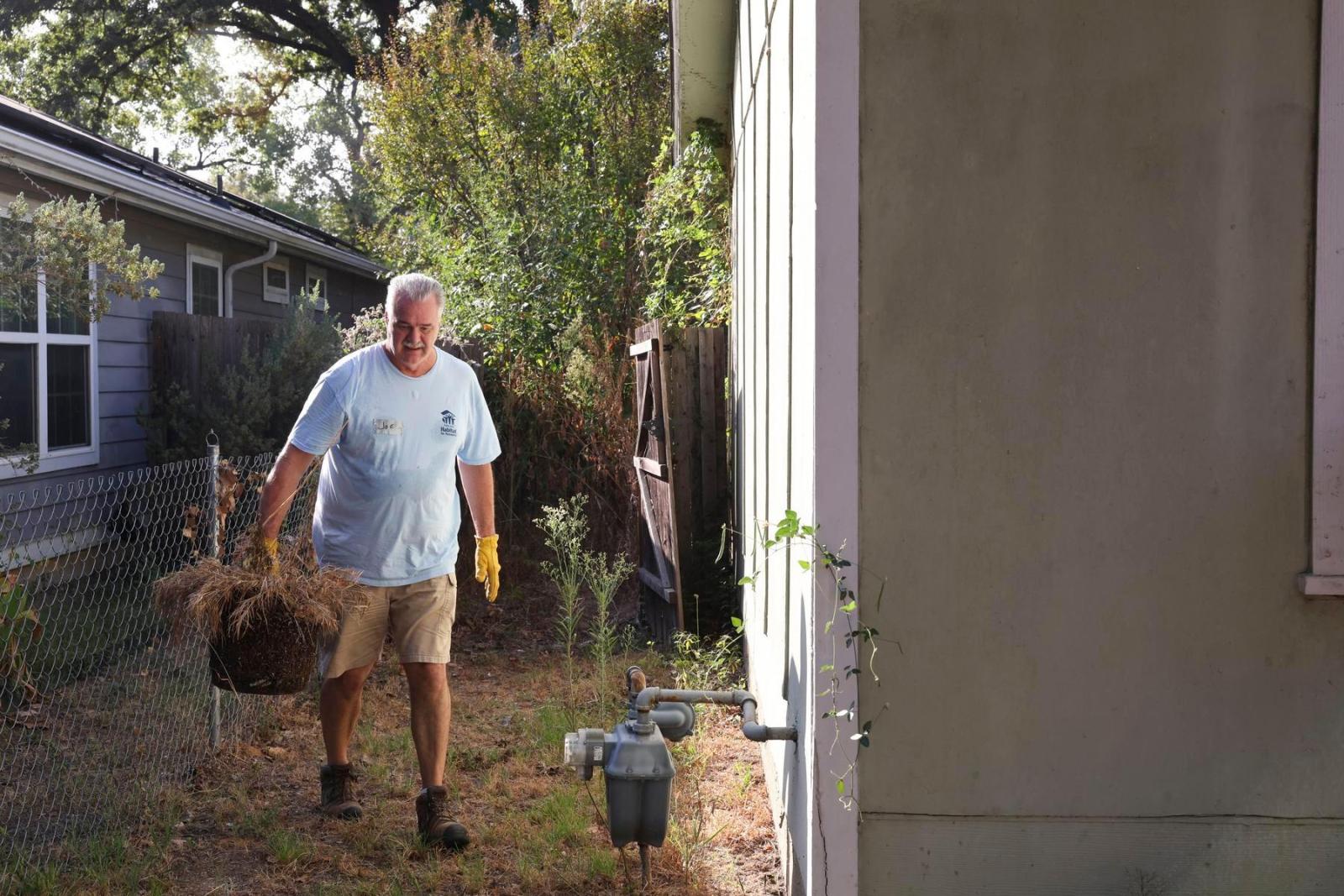 A volunteer walks between two houses while working on a build site.
