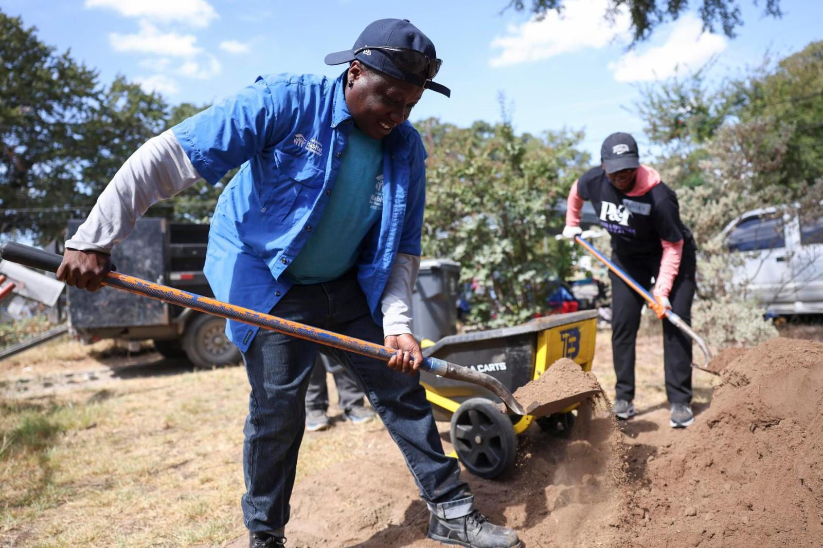A pair of volunteers help clear debris out of a yard.