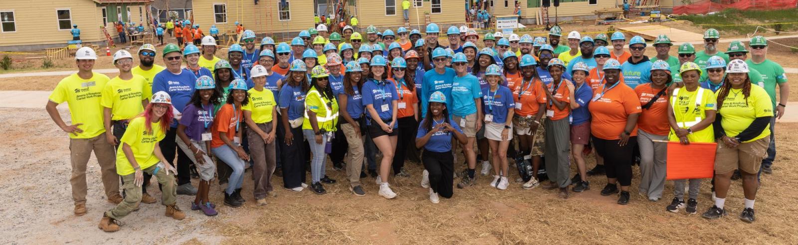 Wide angle shot of large group posing for photo on site of 2026 Carter Work Project in Atlanta.