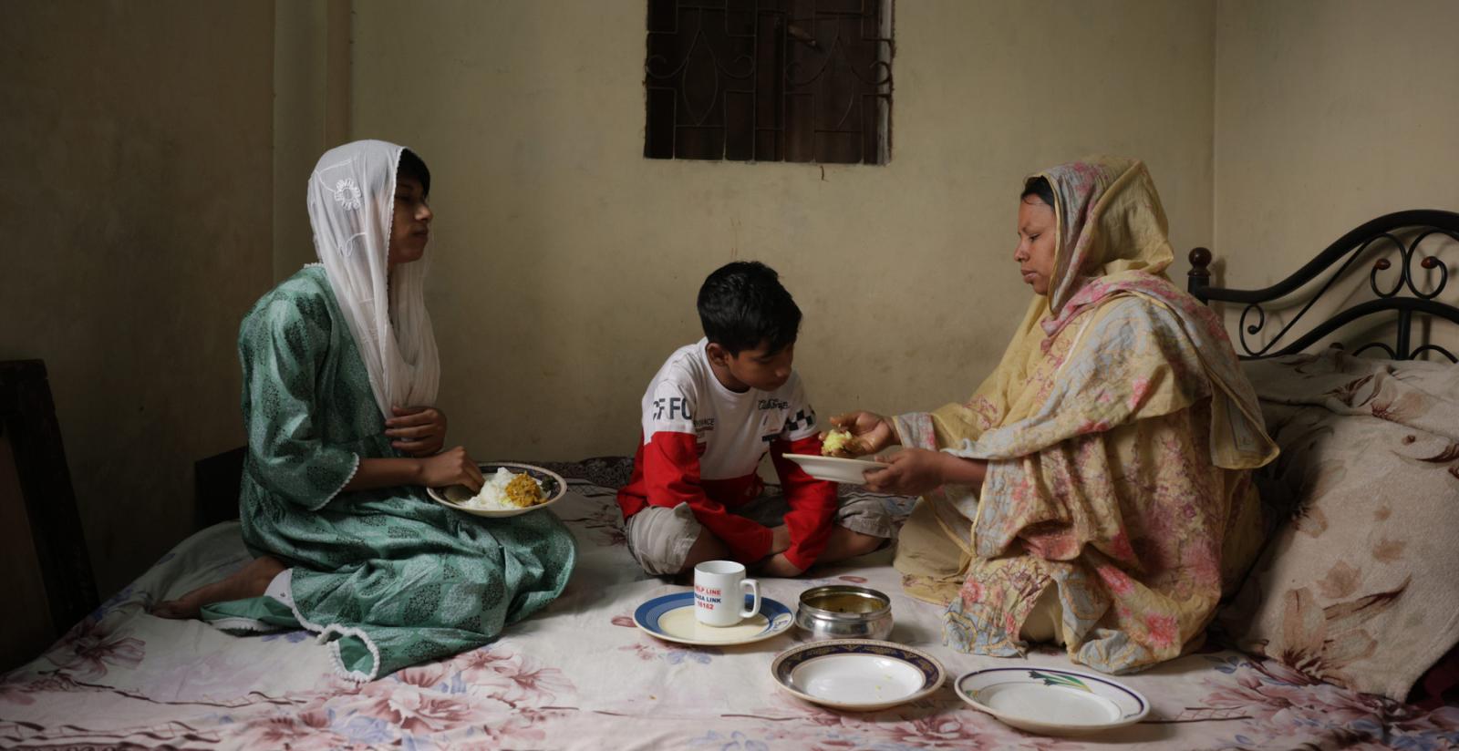 Duaripara informal settlement in Dhaka. Sumi eats a meal with her two children Gim, 10, and Chandri, 17, at their home in Duaripara.