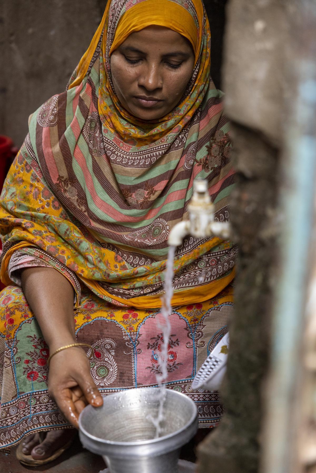 Sahana is able to retrieve safe drinking water from a neighbor's home nearby in Duaripara.