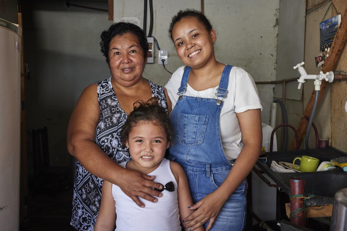 A family of three Brazilian woman smiling at the camera.