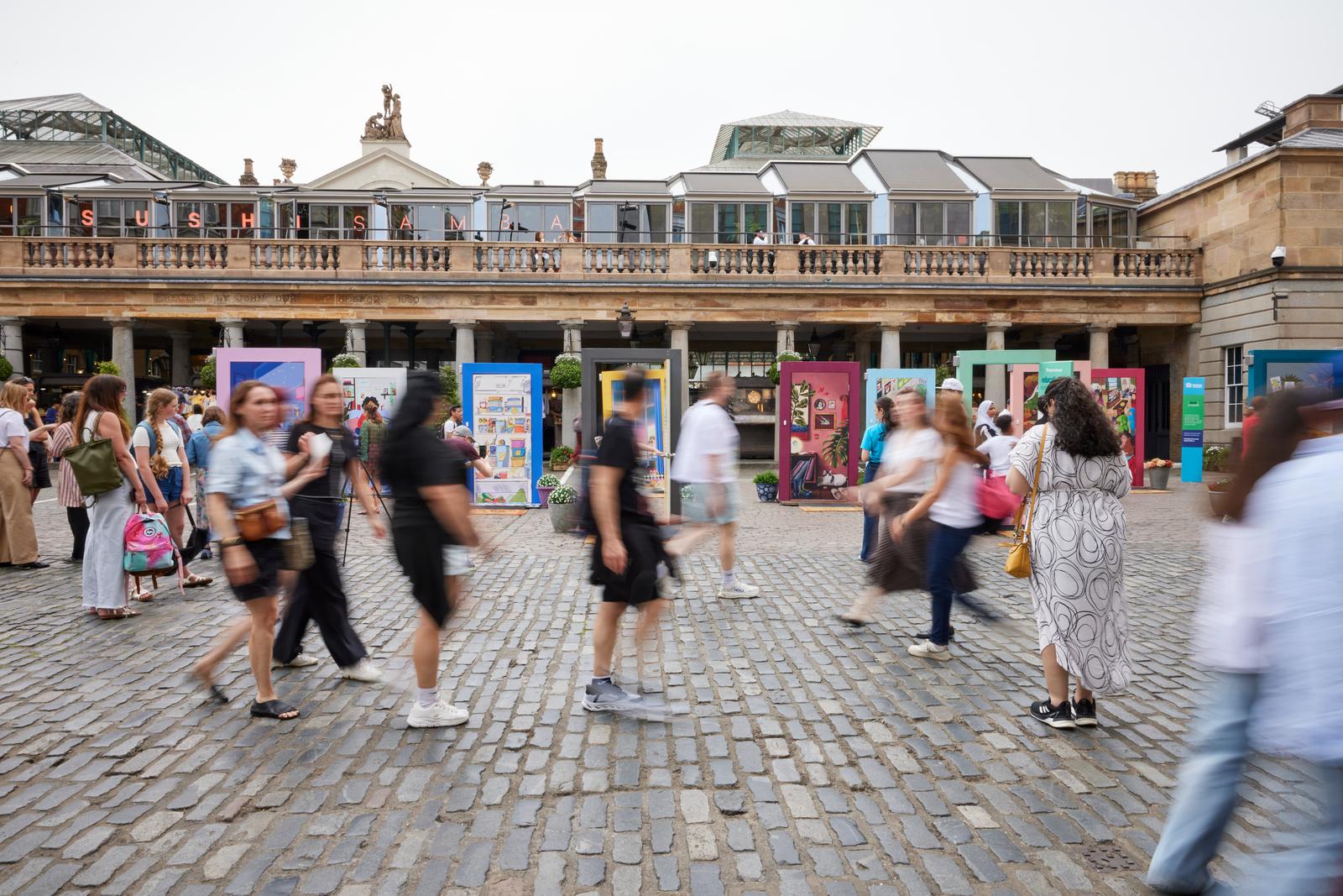 Group of people walking past the pop-up door exhibit in London.