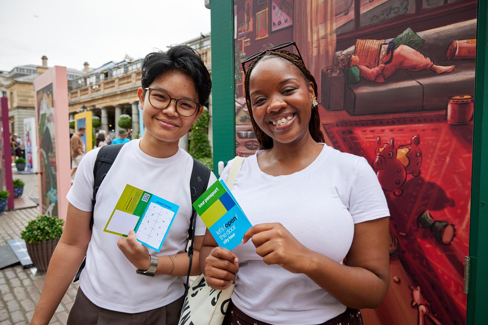 Two individuals in white shirts and Habitat passports smiling in front of an illustrated door.